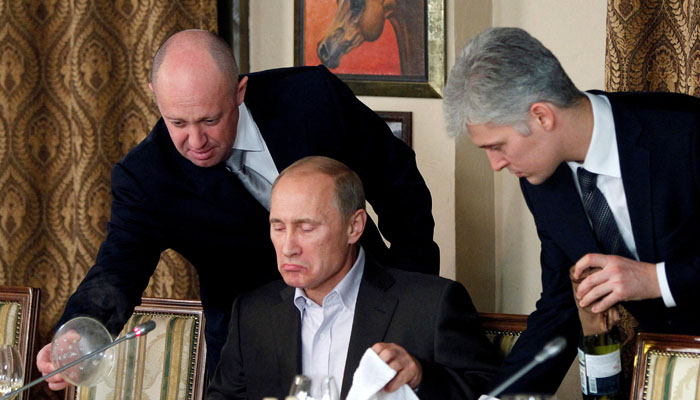 Yevgeny Prigozhin assists Russian Prime Minister Vladimir Putin during a dinner with foreign scholars and journalists at the restaurant Cheval Blanc outside Moscow. — Reuters