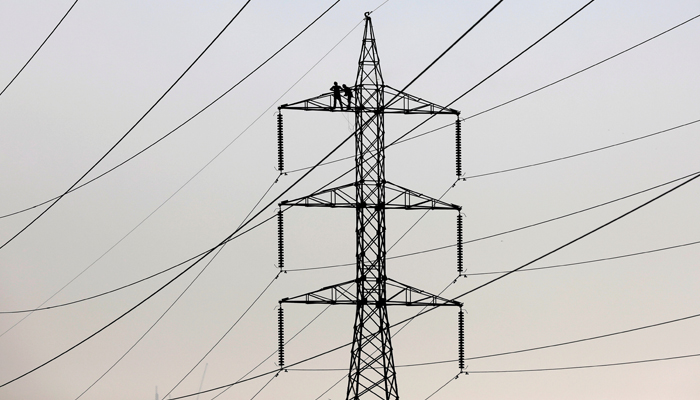 Technicians work to clean power transmission tower in Karachi, Pakistan, December 7, 2018. — Reuters