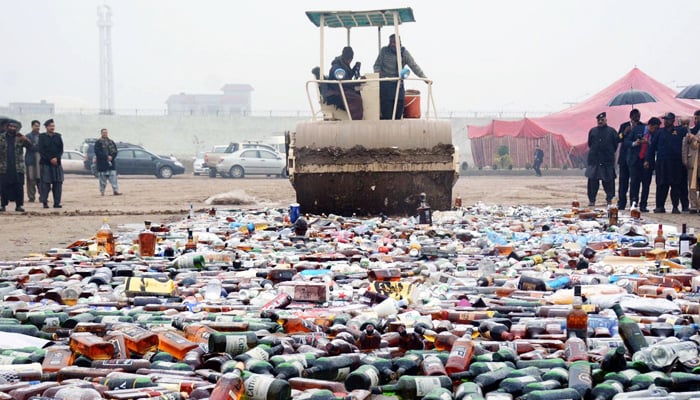 Customs officials destroy bottles of liquor. — INP/File