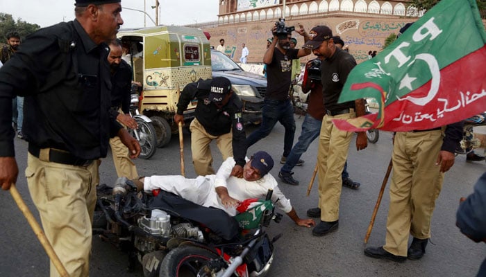 Police personnel arrest a PTI supporter on MA Jinnah Road in Karachi on August 27, 2023. — PPI