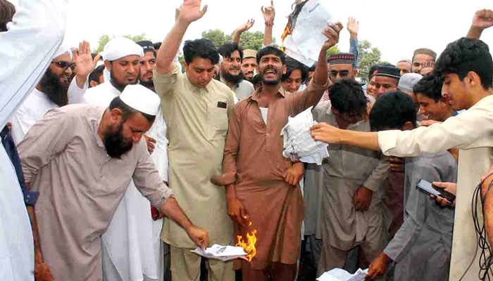 Residents of Peshawars Sethi Town burn electricity bill during protest. —INP