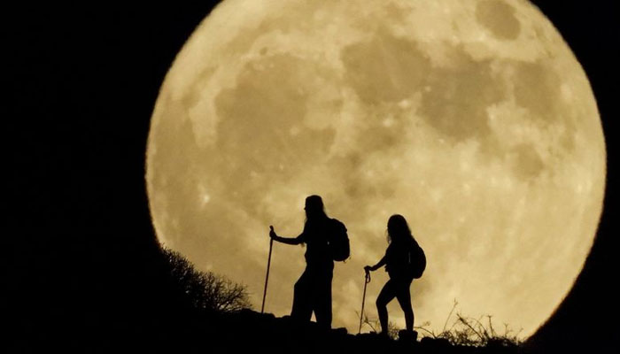 This picture shows a super blue moon behind two women hiking on a hill. — Reuters/File