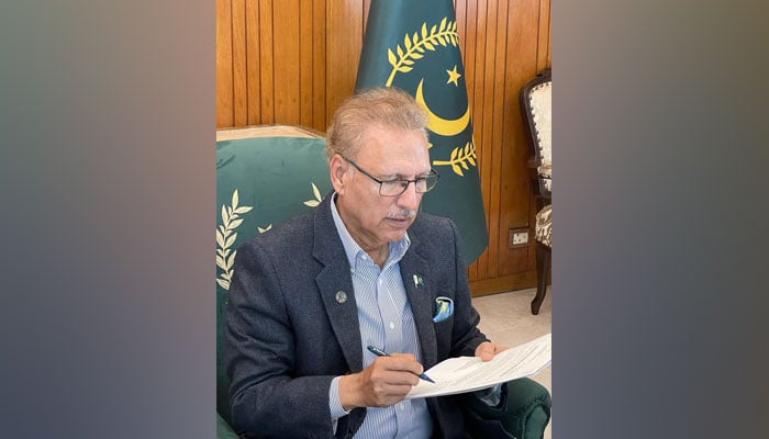 President Arif Alvi signing a a document in this undated picture. — PID