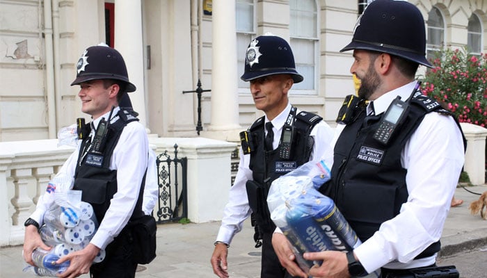 Police officers carry canisters of nitrous oxide, known as laughing gas, confiscated from revellers planning to use it as a drug, during the Notting Hill Carnival in west London on August 29, 2022. — AFP/File