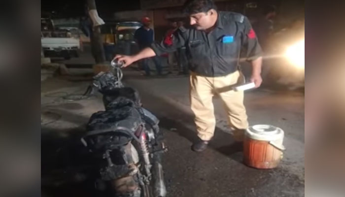 A policeman can be seen examining the motorcycle set on fire by the dishearten online bike rider in this still taken from a video on September 2, 2023. — YouTube/Geo News