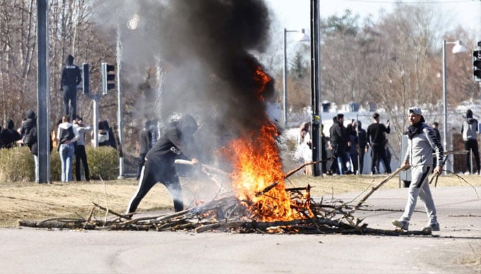 Protesters build a burning barricade on a street during rioting in Norrkoping, Sweden on April 17, 2022.—AFP