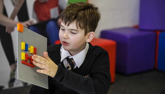 A visually impaired student builds a structure with braille Lego bricks. — Lego/File