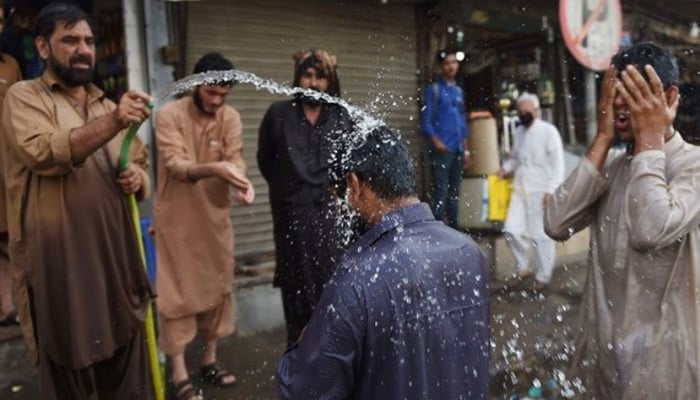 People spray each other with water during hot weather in Karachi. — AFP/File
