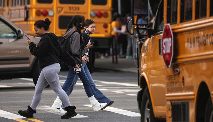 Students walk in a school parking area surrounded by school buses and other vehicles. — Reuters/File