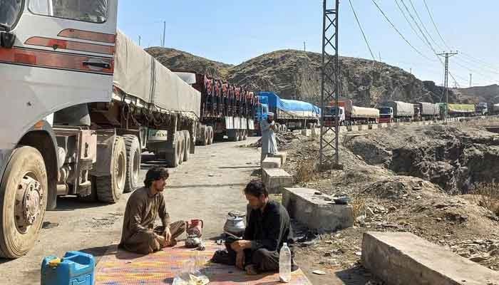 Men sit near a queue of trucks loaded with supplies to leave for Afghanistan, after Taliban authorities have closed the main border crossing in Torkham, Pakistan February 21, 2023. — Reuters