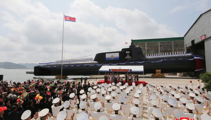 A newly launched tactical nuclear submarine can be seen in the background as the North Korean leader Kim Jong Un lauds the ceremony in this picture released on September 7, 2023. — KCNA