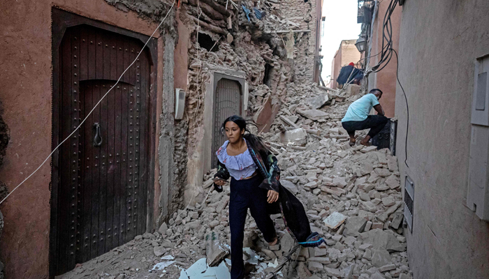 A woman walks with her belongings through the rubble in the earthquake-damaged old city in Marrakesh on September 9, 2023. — AFP