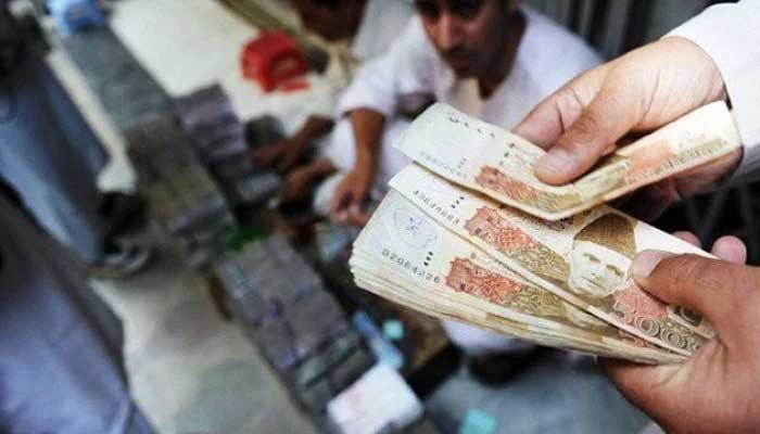 An image of a cashier counting Rs5,000 bank notes — SBP