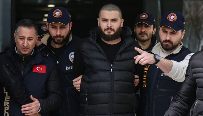 Faruk Fatih Ozer being escorted out of a police facility in Turkey by officers. — X/@Selene406
