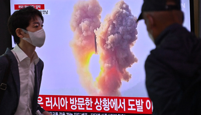 A man walks past a television screen showing a news broadcast with file footage of a North Korean missile test, at a railway station in Seoul on September 13, 2023. — AFP