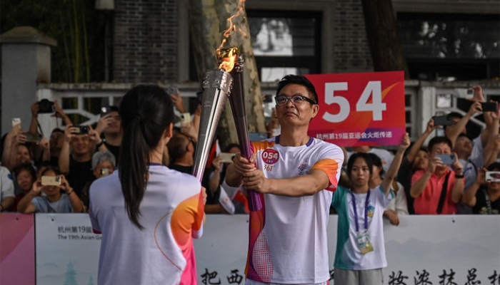 Jiaxing Ye (L), a traditional Chinese ceramist, and writer Mai Jia exchange the flame during the Asian Games torch relay in Hangzhou, China, on September 8, 2023. — AFP