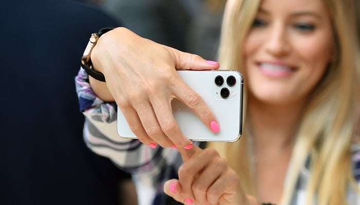 A woman uses iPhone 12 during an Apple promotional event. —AFP/File