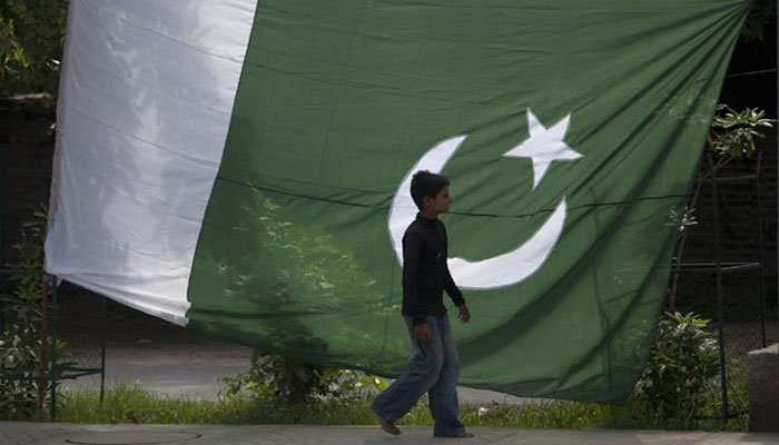 A boy walks past a Pakistani flag displayed for sale ahead of Pakistans Independence Day. — Reuters/File