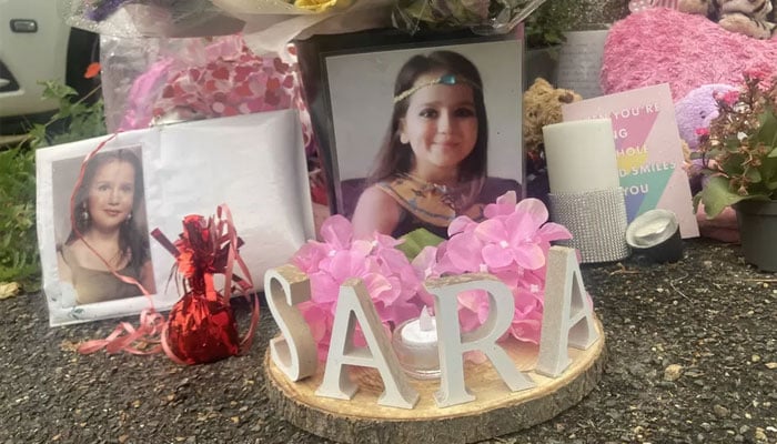 Flowers and pictures of Sarah outside the family home in Woking, Surrey.—Twitter/file