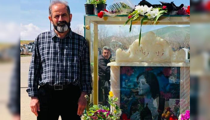 Amjad Amini, Mahsa Aminis father stands next to her grave in Saqez. — X/@LightofRev