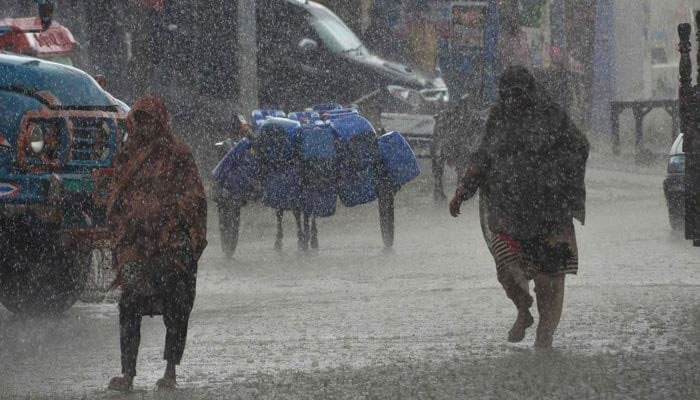 Women walk amid heavy rainfall in Pakistan. — AFP/File