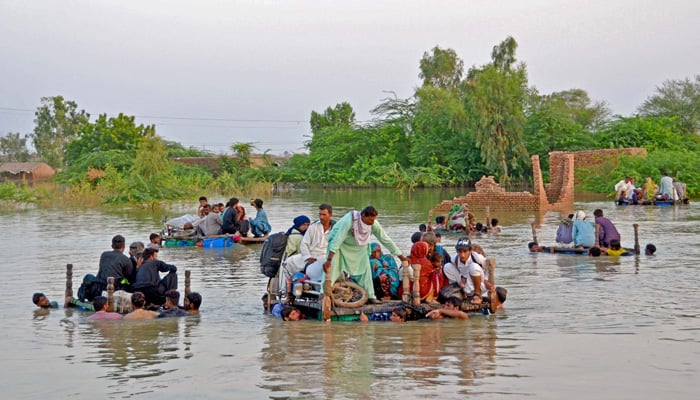 Internally displaced people wade through floodwaters after heavy monsoon rains in Jaffarabad district in Balochistan province on September 8, 2022. — AFP