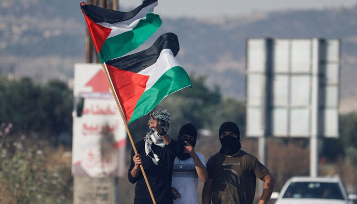 Palestinians hold the Palestinian flag during a protest over tensions in Jerusalems Al-Aqsa Mosque, at Huwara checkpoint, near Nablus in the Israeli-occupied West Bank on May 29, 2022. — Reuters