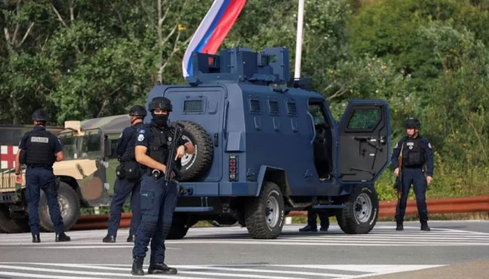 Kosovo police at the scene with troops from the US and EU states in the background.— Reuters