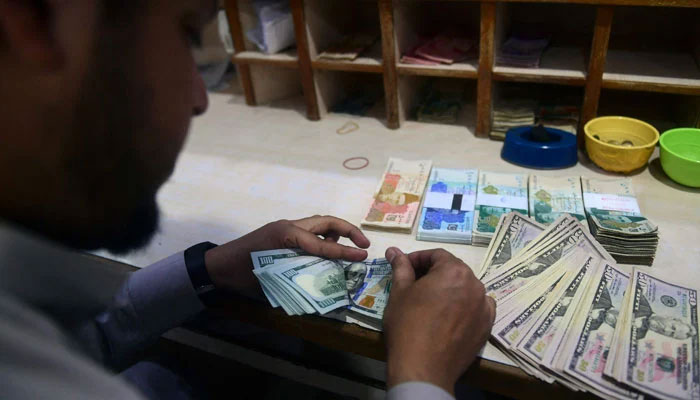 A dealer counts US dollars at a money exchange market in Karachi on January 26, 2023. — AFP