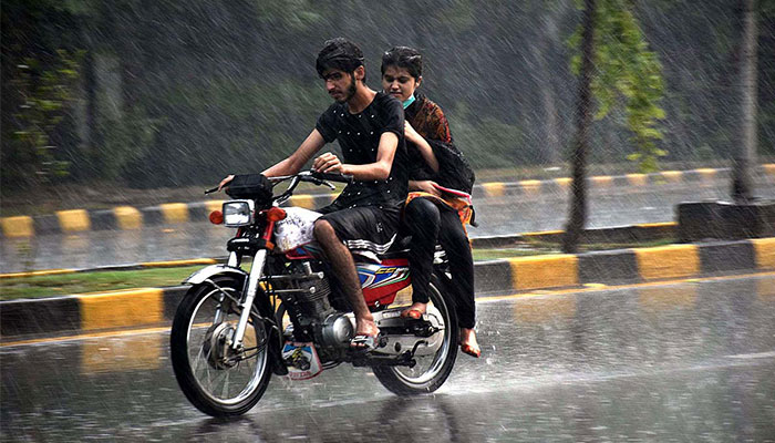 A man and a woman ride on a motorcycle during heavy rain in Lahore. — APP/File