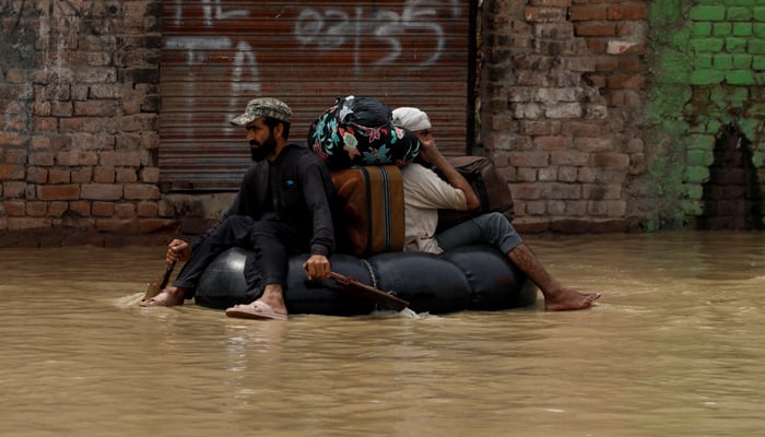 A volunteer paddles an inflatable tube as he evacuates a flood victim with his belongings, following rains and floods during the monsoon season in Charsadda, Pakistan August 27, 2022. — Reuters
