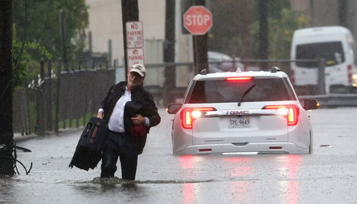 A man carries his belongings as he abandons his vehicle which stalled in floodwaters during a heavy rain storm in the New York City suburb of Mamaroneck in Westchester County, New York, US, September 29, 2023.—Reuters