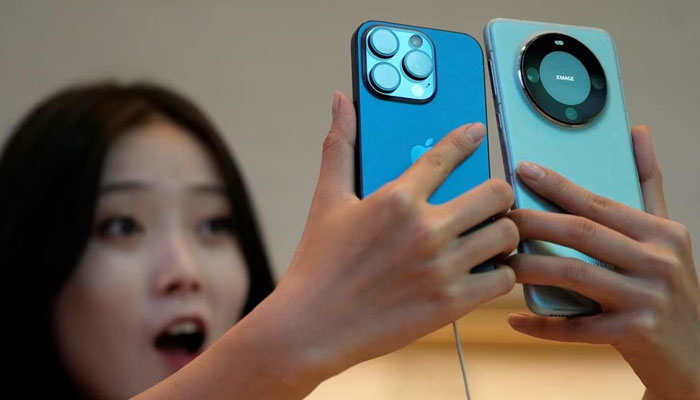 A woman looks at a new iPhone 15 Pro and a Huawei Mate 60 Pro as Apples new iPhone 15 officially goes on sale across China, at an Apple store in Shanghai, China September 22, 2023.—Reuters