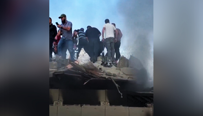 Palestinians celebrating on top of an Israeli tank in Palestine, on  October 7, 2023, in this still taken form a video. — X/@AlArabiya_Eng