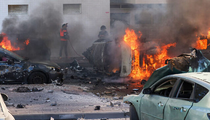 People try to extinguish cars following a rocket attack from the Gaza Strip in Ashkelon, southern Israel, on October 7, 2023. — AFP