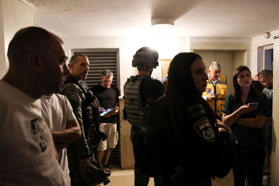 Israeli security personnel and members of the media take shelter as a siren sounds while rockets are launched from the Gaza Strip, in Mevaseret Zion, Israel October 7, 2023. — Reuters