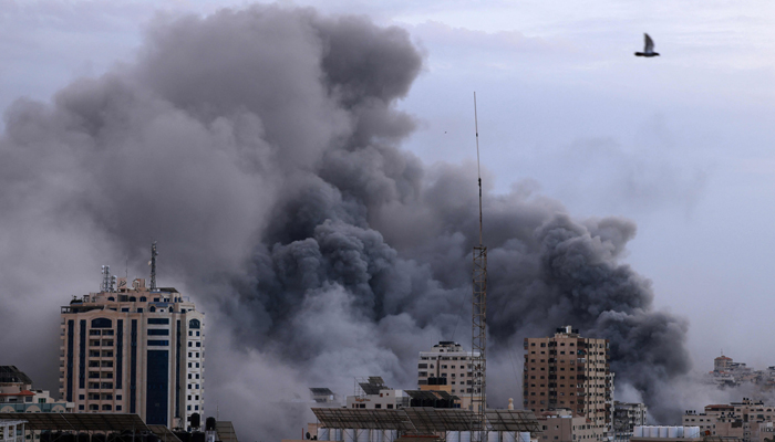 A black plume of smoke billows behind highrise buildings during an Israeli airstrike on Gaza City on October 9, 2023. — AFP
