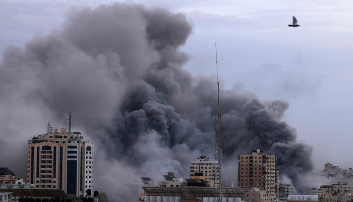 A black plume of smoke billows behind highrise buildings during an Israeli airstrike in Gaza City on October 9, 2023. — AFP