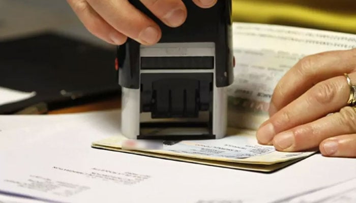 Representational image of a visa officer issuing visa on a travellers passport. — Reuters/File