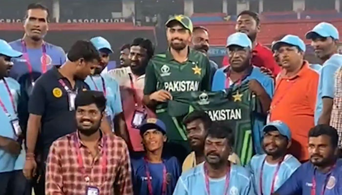 Pakistan captain Babar Azam poses with the ground staff at Hyderabad handing them over his jersey as a souvenir. — Instagram/@icc