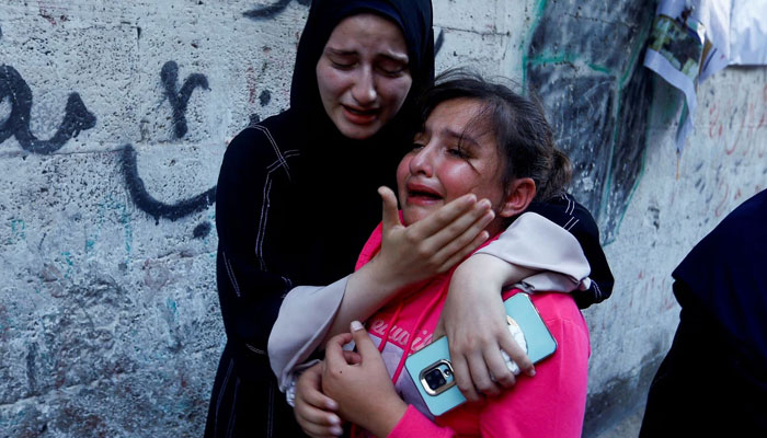 The daughter of Zakaria Abu Maamar, a member of Hamas political office, is comforted as she cries during her fathers funeral, after he was killed in an air strike, in Khan Younis, in southern Gaza Strip, October 10. —Reuters