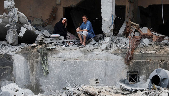 Palestinians sit among the rubble of a damaged residential building, in the aftermath of Israeli strikes, in Gaza City, on October 10. —Reuters