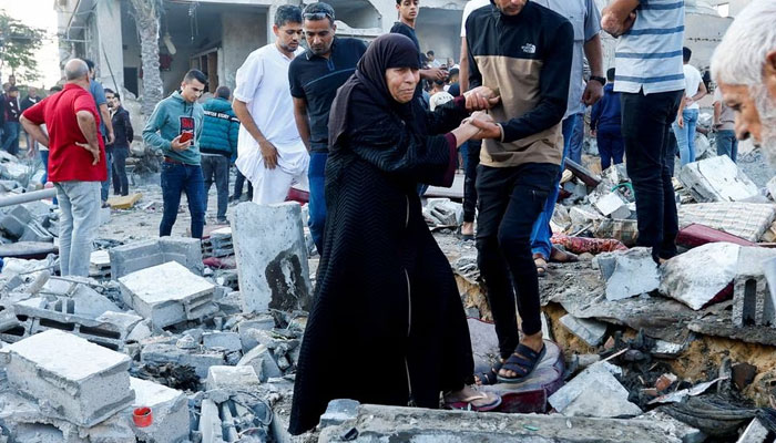 People walk on rubble in the aftermath of a strike amid the conflict with Israel in Khan Younis, in the southern Gaza Strip, October 12, 2023. — Reuters