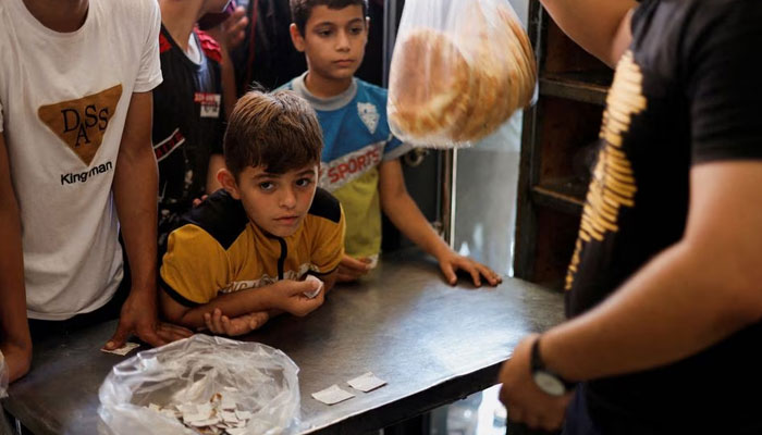 Palestinians wait to buy bread outside a bakery, amid the ongoing conflict between Israel and Palestinian Islamist group Hamas, in Khan Younis in the southern Gaza Strip October 14, 2023.