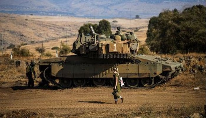 An Israeli soldier walks past a tank amid heightened tensions between Israel and Lebanon, as seen from the border with Lebanon in northern Israel, October 14, 2023.—Reuters