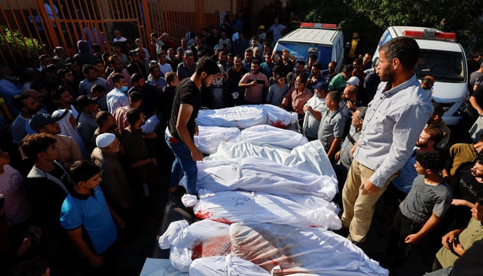 Mourners stand near the bodies of Palestinians who were martyred in Israeli strikes, in Khan Younis, in the southern Gaza Strip. — Reuters