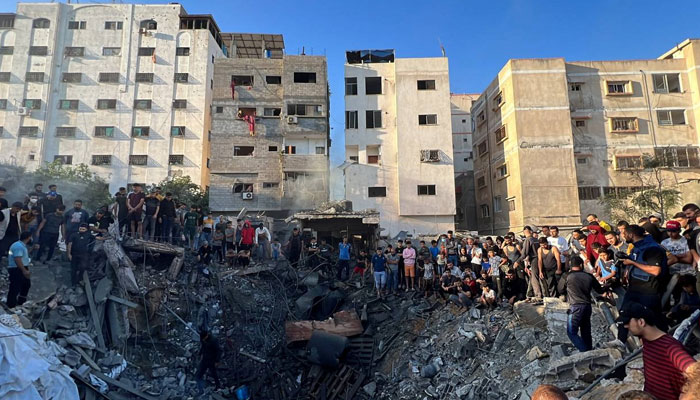 Palestinians gather at the site of an Israeli strike on a house, amid the ongoing conflict between Israel and Hamas, in Gaza City on October 21, 2023. — Reuters