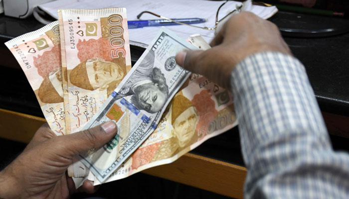 A money changer displays Pakistani notes of Rs5,000 with one bill of USD100. — Online/File