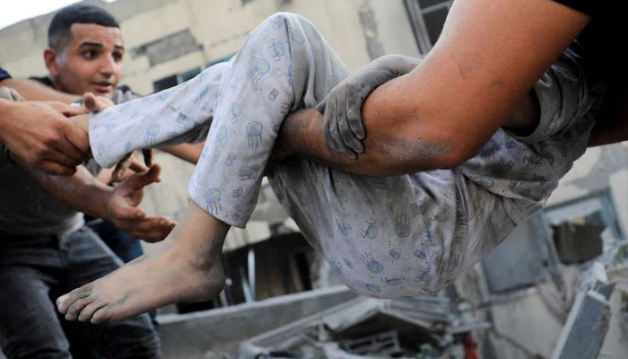 A Palestinian child is assisted as people search for casualties at the site of an Israeli strike on a residential building in Gaza City, October 25.—Reuters
