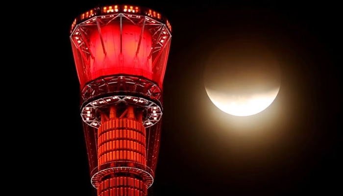 A shadow falls on the moon, as seen beside the worlds tallest broadcasting tower Tokyo Skytree, during a partial lunar eclipse in Tokyo, Japan November 19, 2021. — Reuters